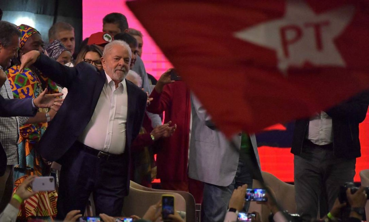 Lula é visto ao lado de bandeira do PT agitada por apoiador durante lançamento da pré-candidatura Foto: NELSON ALMEIDA / AFP