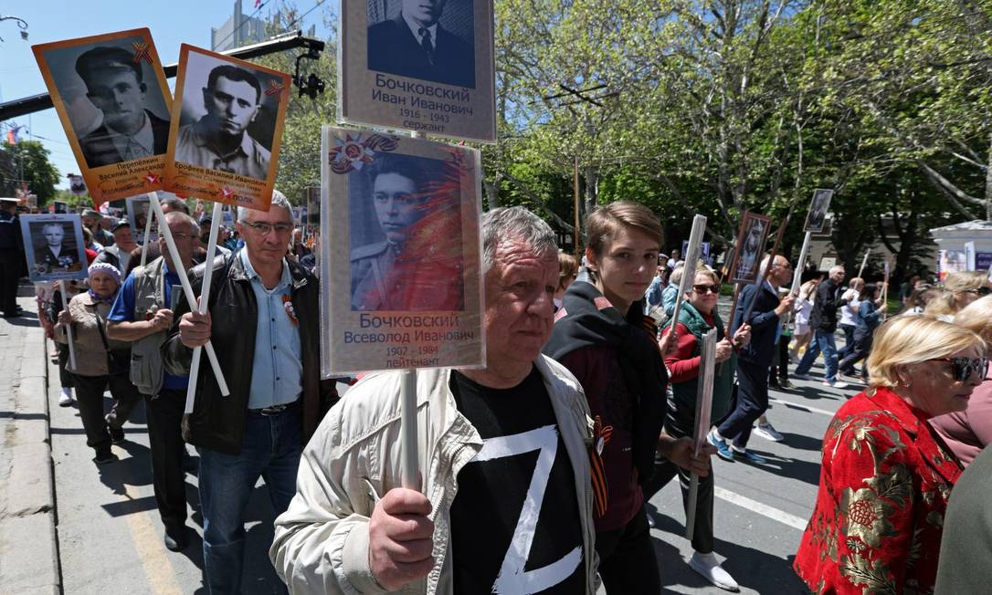 Marcha nesta segunda-feira em Sebastopol, na Crimeia, por ocasião do Dia da Vitória soviética sobre o nazismo; homem carrega foto de soldado enquanto usa camisa com Z, símbolo da agressão contra a Ucrânia Foto: ALEXEY PAVLISHAK / REUTERS