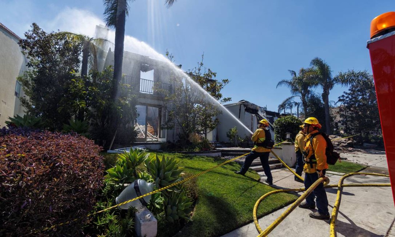 A firefighter sprays water on the remains of a burned-out home after a fast-moving wildfire ripped through an affluent neighborhood in Laguna Niguel, California, U.S., May 12, 2022. REUTERS/Mike Blake Foto: MIKE BLAKE / REUTERS