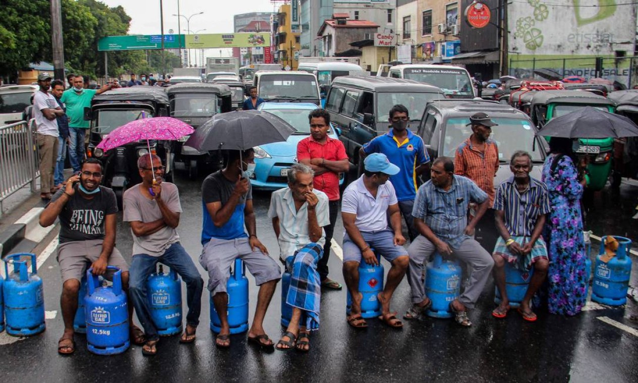 Pessoas sentadas em cilindros de gás vazios bloqueiam estrada para protestar contra a escassez de combustível e gás de cozinha em Colombo, no Sri Lanka Foto: - / AFP