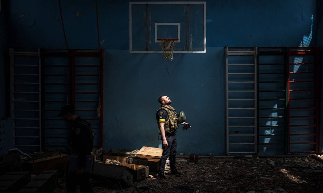 Policial ucraniano é visto dentro de quadra de esportes de escola onde, segundo moradores, soldados russos usavam como base na vila de Vilkhivka, perto de Kharkiv Foto: DIMITAR DILKOFF / AFP