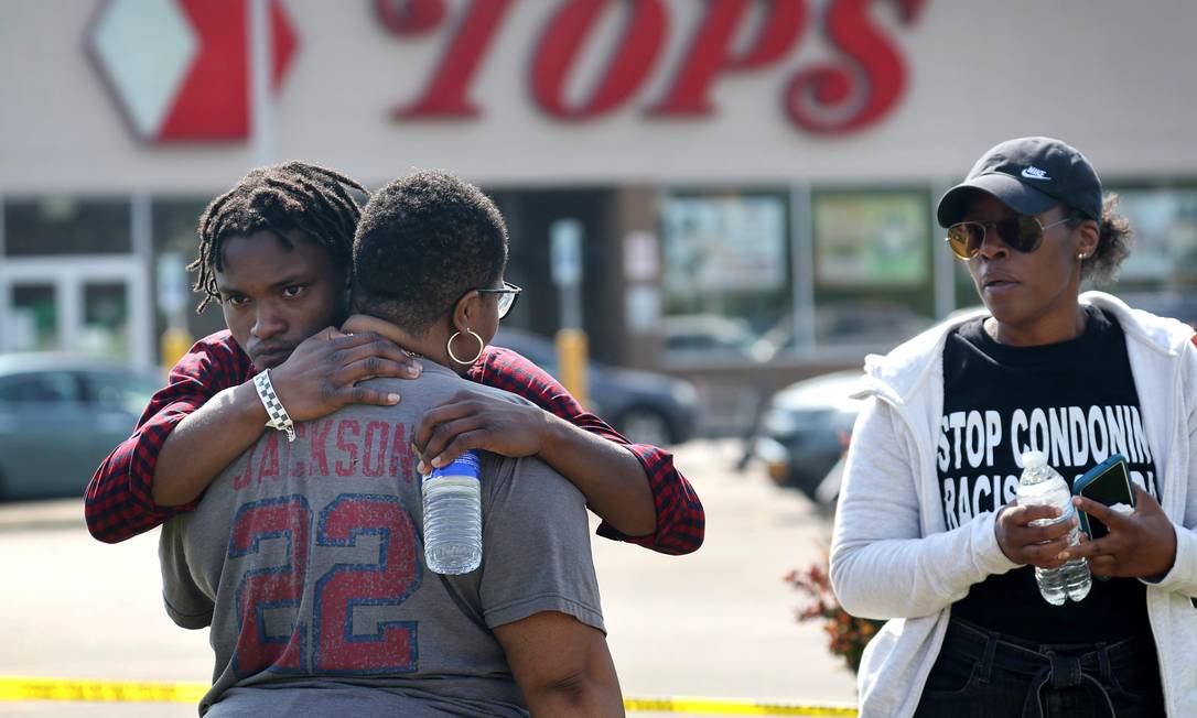 Pessoas se abraçam fora do mercado Tops, em Buffalo, Nova York, um dia após um homem branco de 18 anos matar dez pessoas e ferir outras três em um ataque descrito por autoridades como puramente racista Foto: Scott Olson / AFP