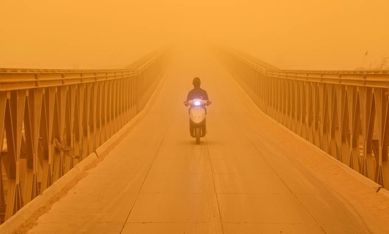 Motorista dirige uma scooter em meio a forte tempestade de poeira, ao longo de uma ponte na cidade de Nasiriyah, na província de Dhi Qar, no sul do Iraque Foto: SABAH ARAR / AFP