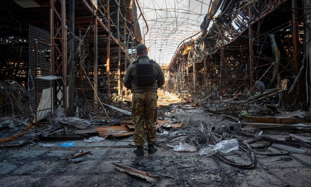 Policial ucraniano documenta a destruição em um dos maiores mercados de roupas da Europa, em Kharkiv, Ucrânia Foto: SERGEY BOBOK / AFP
