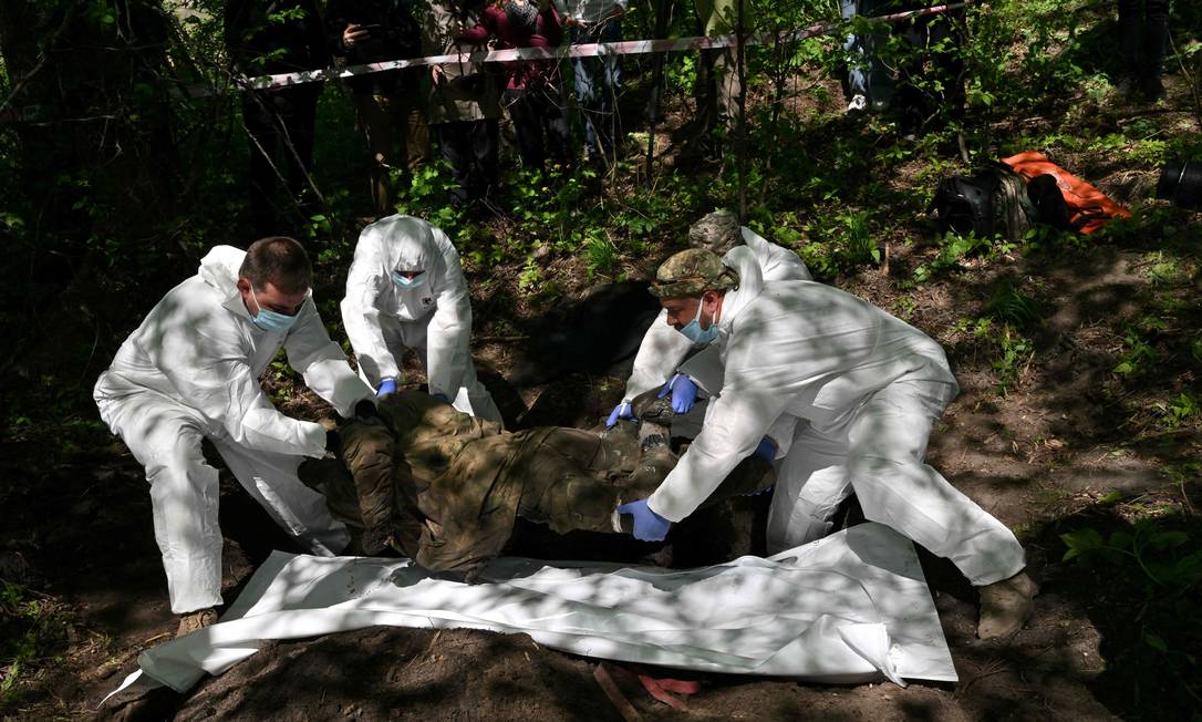 Especialistas forenses exumam o corpo de um soldado russo na vila de Zavalivka, a oeste de Kiev Foto: SERGEI SUPINSKY / AFP