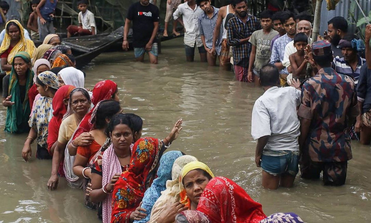 Pessoas afetadas por enchentes fazem fila com água até os joelhos para coletar alimentos em Sunamganj, em Bangladesh Foto: MD ABU SUFIAN JEWEL / AFP