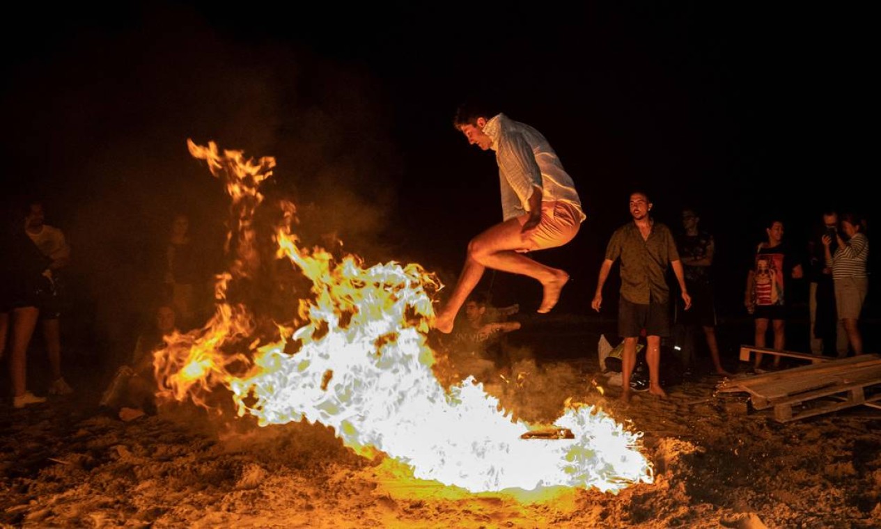 Homem salta uma fogueira durante as celebrações anuais de São João em uma praia em Alicante, Valência, Espanha Foto: JOSE JORDAN / AFP