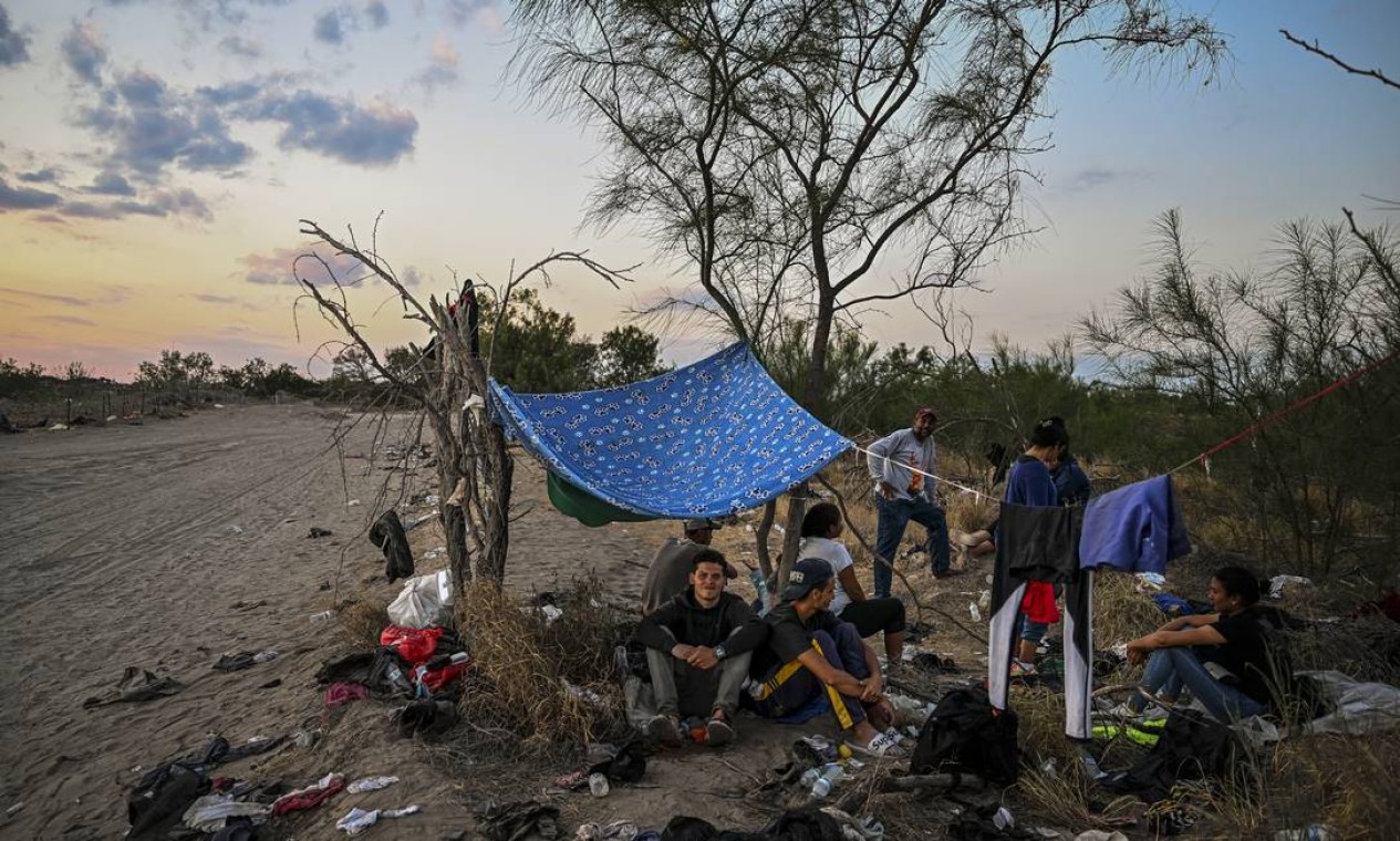 Imigrantes descansam depois de cruzar o Rio Grande enquanto esperam para serem detidos por agentes da Patrulha de Fronteira em Eagle Pass, Texas, na fronteira com o México Foto: CHANDAN KHANNA / AFP