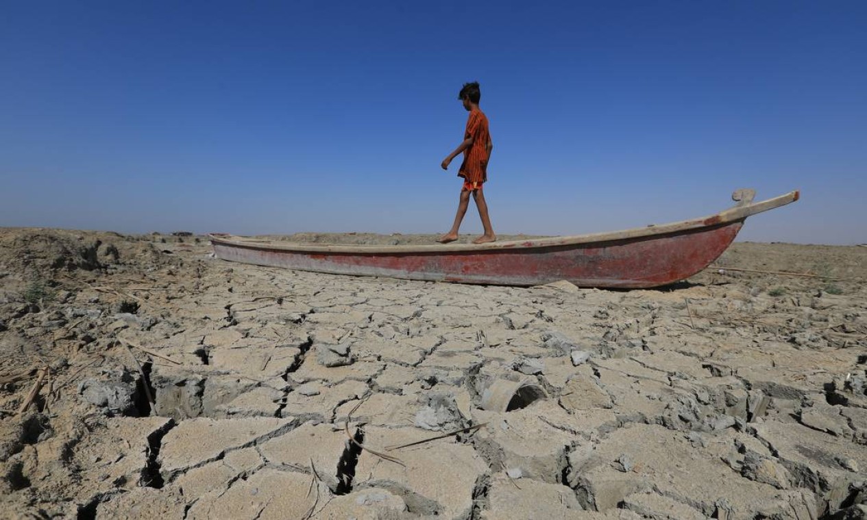 Um menino caminha perto de um barco deixado no leito seco de uma seção dos pântanos do sul do Iraque de Chibayish, na província de Dhi Qar. A seca no Iraque reflete um declínio no nível das vias navegáveis devido à falta de chuva e fluxos mais baixos dos países vizinhos a montante, Irã e Turquia. Foto: ASAAD NIAZI / AFP