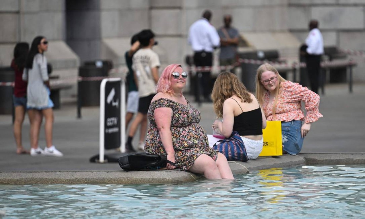 Pedestres se refrescam com os pés na água da fonte de Trafalgar Square, no centro de Londres. A Grã-Betanha emitiu alerta de calor extremo para os próximos dias Foto: JUSTIN TALLIS / AFP