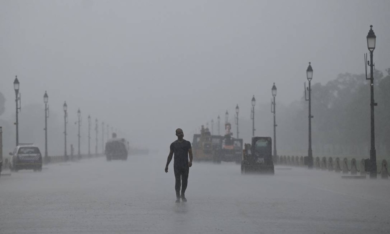 Homem caminha ao longo de Rajpath durante uma chuva de monção em Nova Délhi, Índia Foto: MONEY SHARMA / AFP
