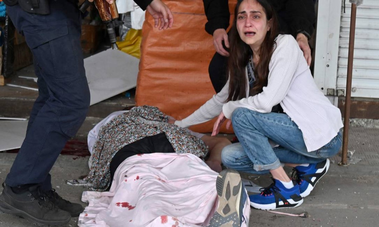 Mulher se desespera ao lado do corpo de seu marido que morreu em um ataque de foguete russo a um dos distritos da segunda maior cidade ucraniana, Kharkiv. Dois civis foram mortos e outros 19 ficaram feridos na última rodada de bombardeio russo Foto: SERGEY BOBOK / AFP