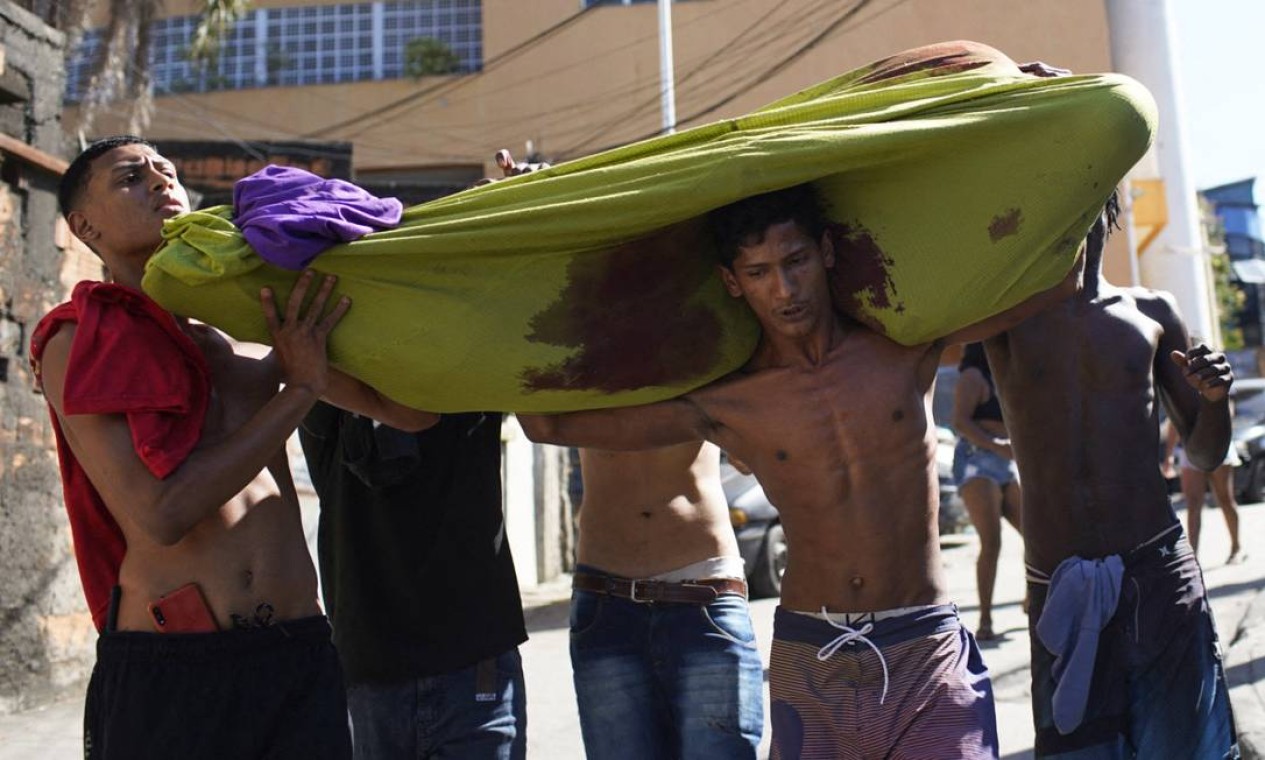 Moradores carregam corpo de vítima da operação policial no Complexo do Alemão Foto: MAURO PIMENTEL / AFP