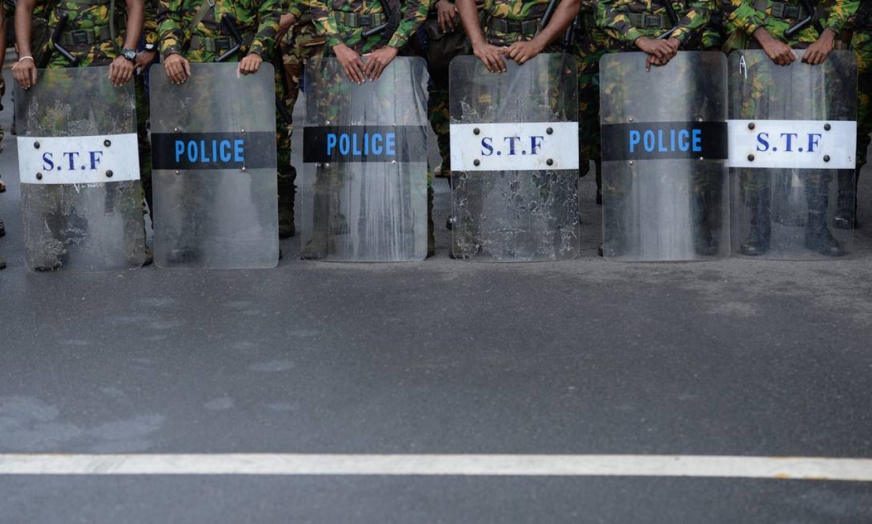 Força-tarefa especial da polícia monta guarda enquanto manifestantes marcham contra o presidente do Sri Lanka, Ranil Wickremesinghe, em direção ao escritório da secretaria presidencial, em Colombo Foto: ARUN SANKAR / AFP