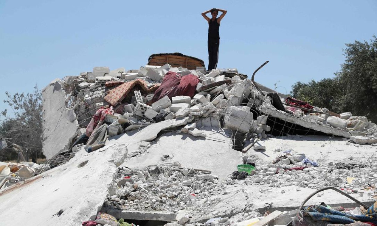Jovem sírio é visto sobre monte de escombros a cidade rebelde de Jisr al-Shughur, na província de Idlib, no noroeste do país, alvo de um ataque aéreo russo, que matou sete pessoas, sendo quatro crianças Foto: OMAR HAJ KADOUR / AFP
