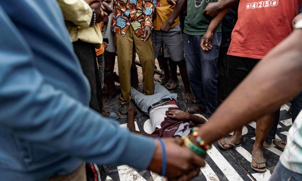 Corpo de homem baleado durante protesto contra missão de paz da ONU é cercado por manifestantes no chão cercado por manifestantes, em uma rua de Goma, leste da República Democrática do Congo Foto: MICHAEL LUNANGA / AFP