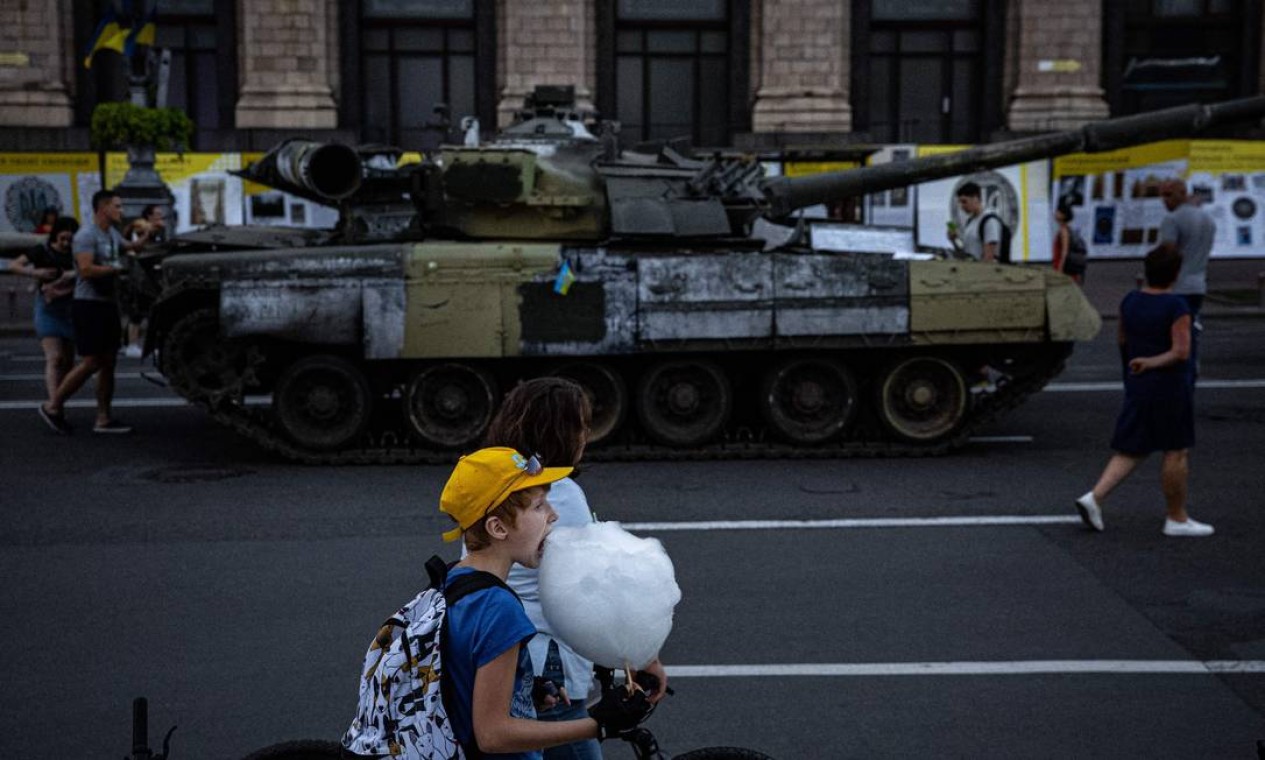 Menino come algodão doce ao lado de tanque de guerra russo destruído que foi transformado em museu, na rua Khreshchatyk, em Kiev Foto: DIMITAR DILKOFF / AFP