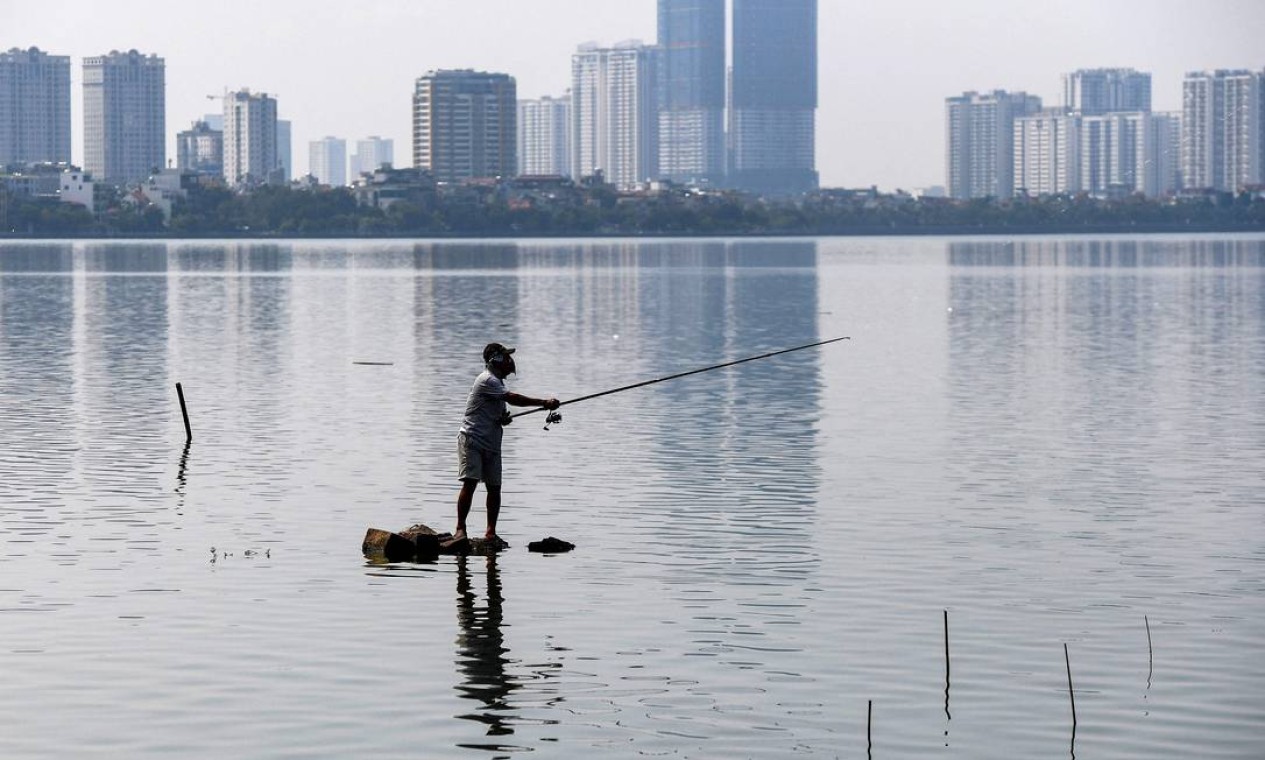Um homem pesca no Lago West, o maior lago de água doce de Hanói, no Vietnã. Foto: NHAC NGUYEN / AFP