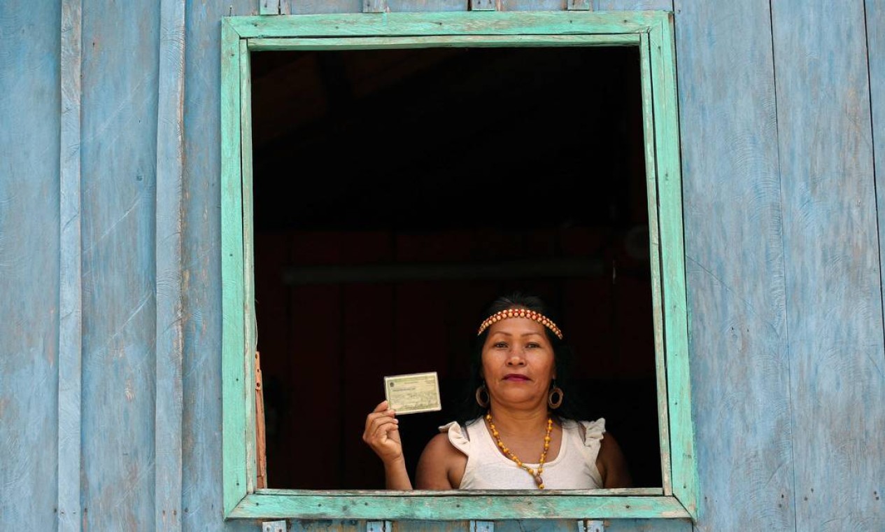 Indígena Kambeba posa com título de eleitor, na Comunidade Três Unidos, no rio Negro, Amazonas Foto: MICHAEL DANTAS / AFP
