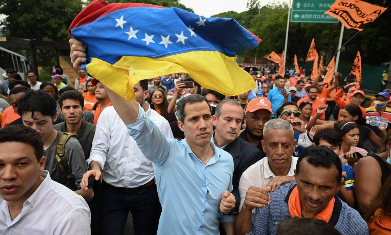 O líder da oposição venezuelana Juan Guaidó agita uma bandeira nacional durante uma manifestação para exigir uma data para as eleições presidenciais, em Caracas Foto: FEDERICO PARRA / AFP