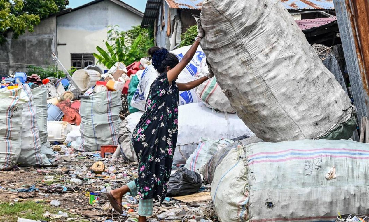 Trabalhador movimenta um saco de garrafas plásticas em um local de coleta de lixo, em Banda Aceh, Indonésia Foto: CHAIDEER MAHYUDDIN / AFP