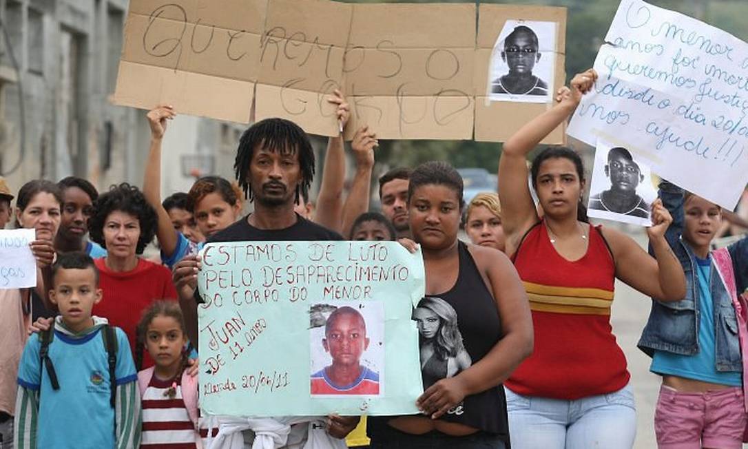 Com uma foto do filho, os pais de Juan de Moraes participam de um protesto em Nova Iguaçu, na Baixada (Foto: Cléber Júnior Extra Agência O Globo)