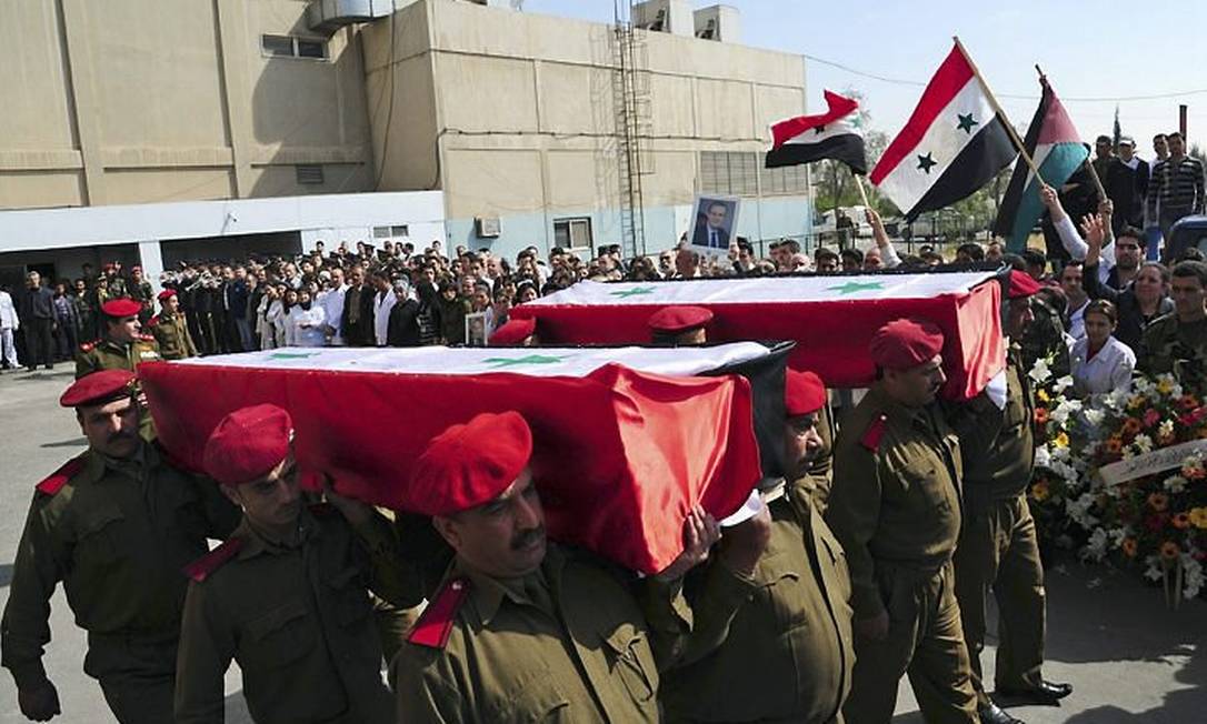Caixões que levariam corpos de soldados e policiais mortos na segunda-feira deixam um hospital em Damasco - AP