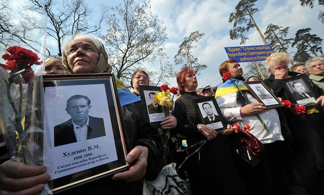 Mulheres que ficaram viúvas após o desastre em Chernobyl mostram retratos dos maridos - AFP