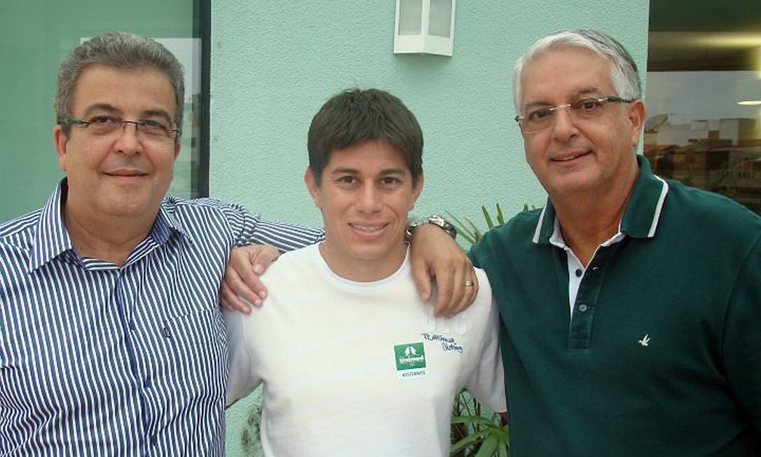 Após a assinatura do contrato, Conca entre o presidente da Unimed, Celso Barros, e o vice-presidente de futebol do Fluminense, Alcides Antunes. Foto de divulgação