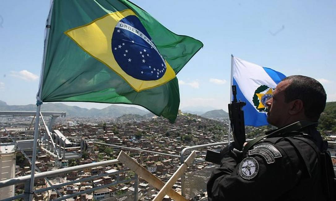 Policiais hasteiam bandeira do Brasil no alto do teleférico do Alemão. Foto: Bruno Gonzalez