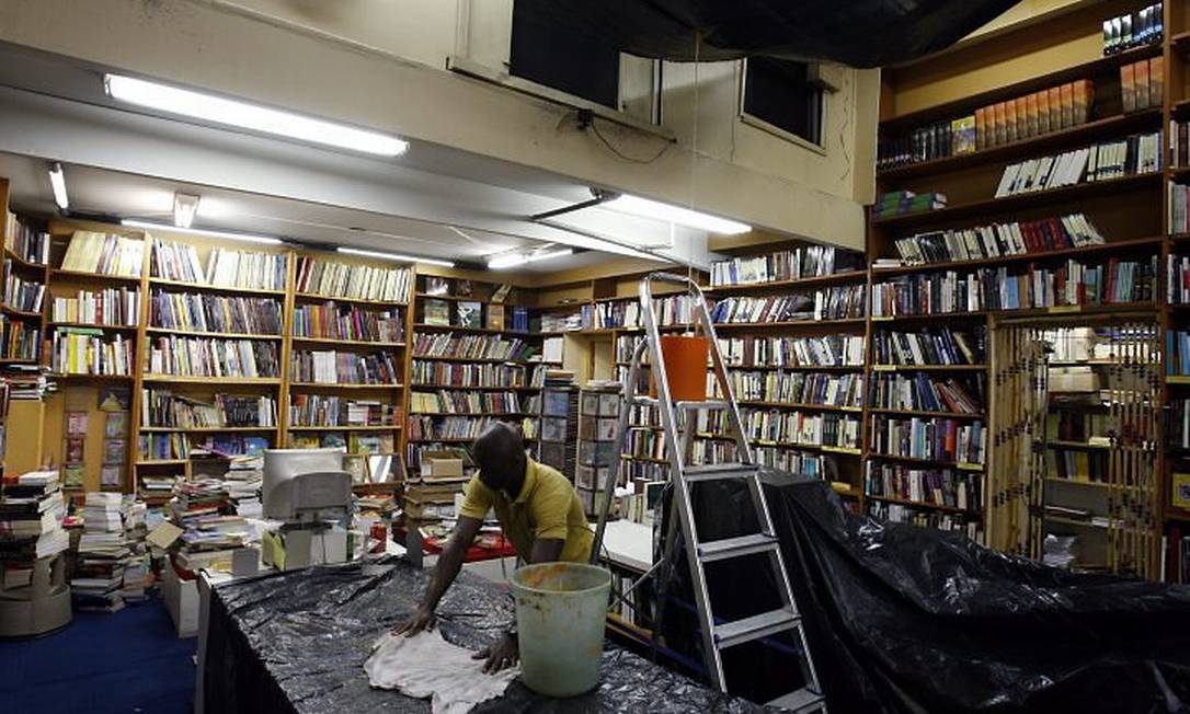 UM FUNCIONÁRIO da Leonardo da Vinci tenta secar a água suja que escorre do teto da livraria, no Centro Foto de Domingos Peixoto - O Globo