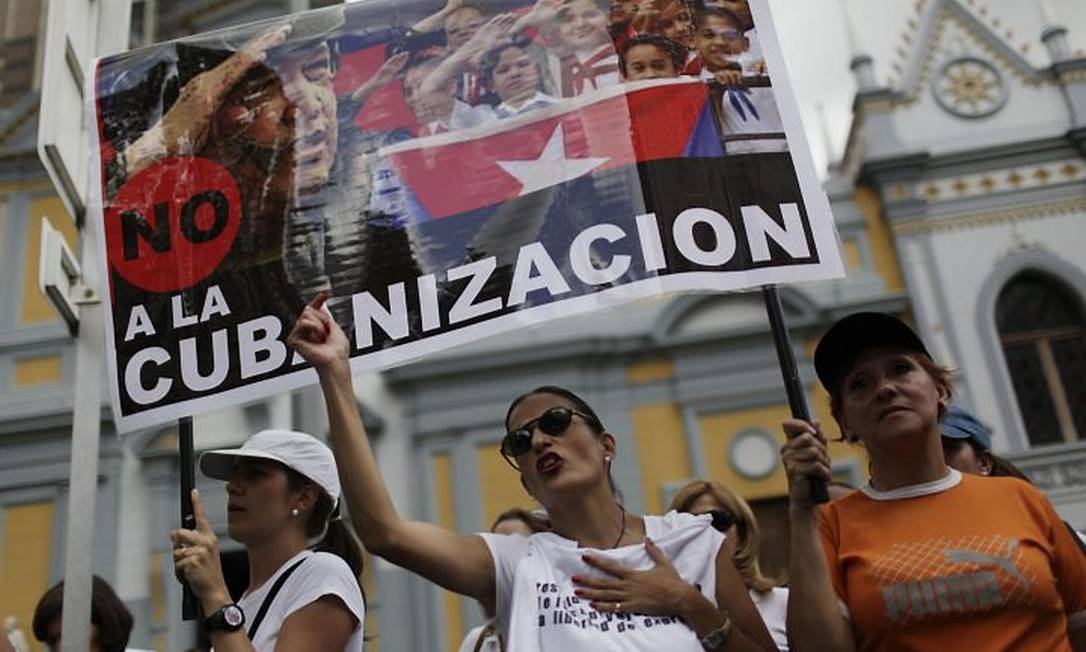 Opositores marcham com cartaz que se lê 'não à cubanização' durante protesto contra a reforma da educação na Venezuela - AP