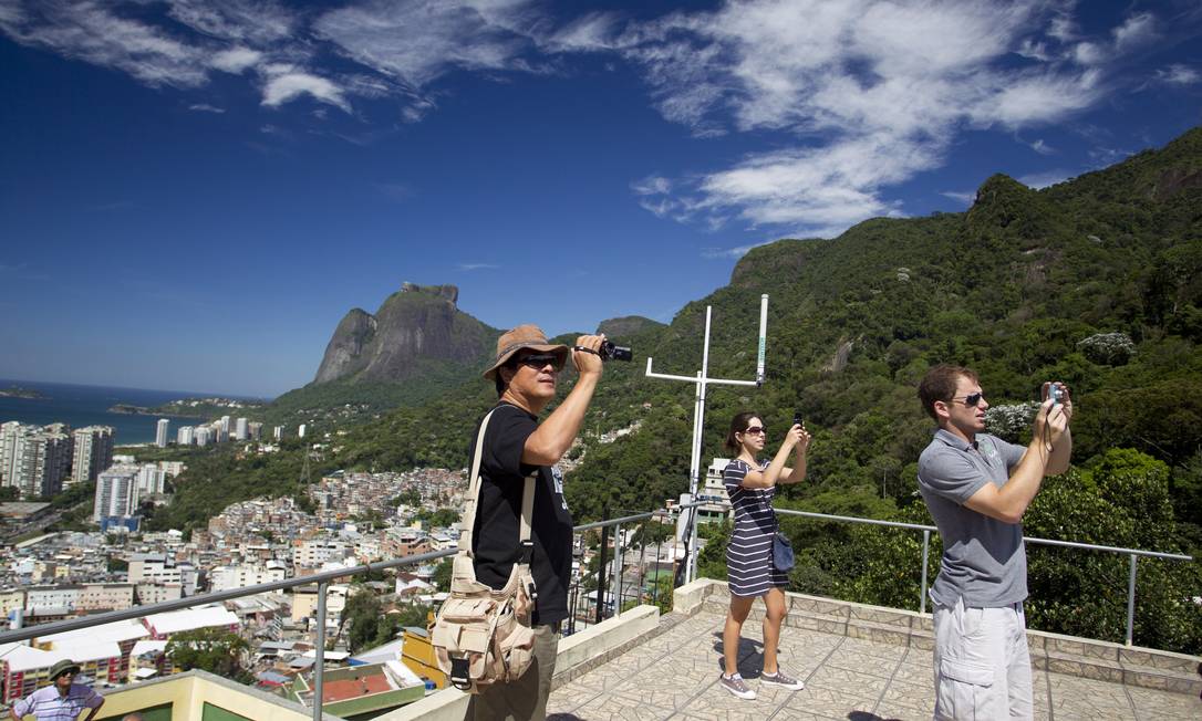 Turistas estrangeiros filmam a paisagem no entorno da Laje do Carlinhos, na entrada da Rua 1, na Rocinha
Foto: Márcia Foletto / O Globo