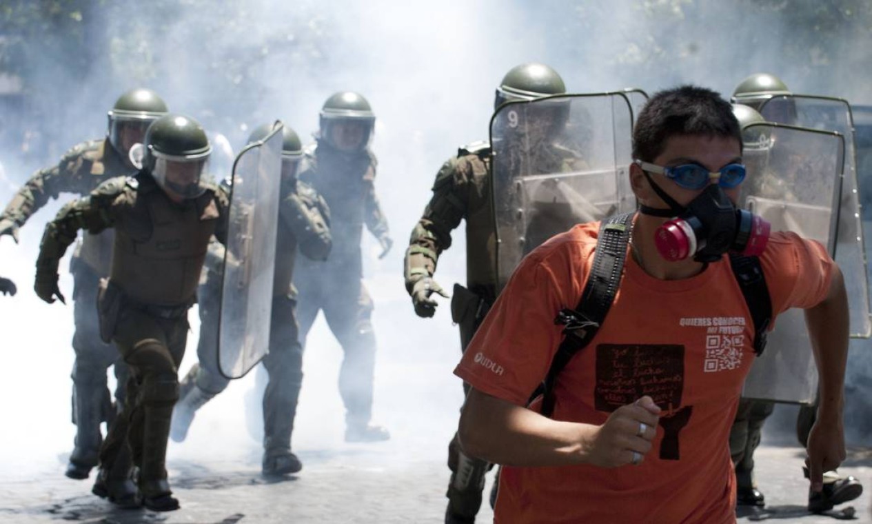 Jovem usando máscara de gás e óculos de piscina foge de policiais na capital Foto: CLAUDIO SANTANA / AFP