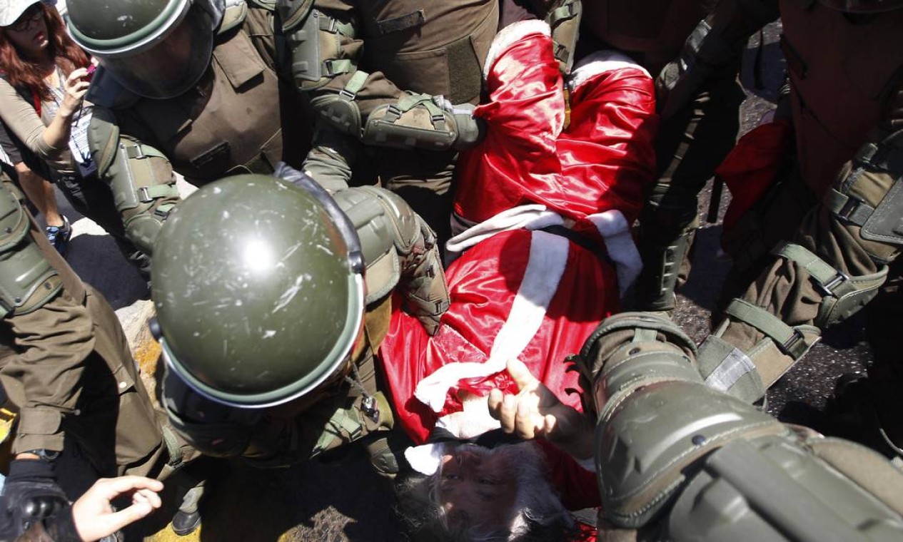 Manifestante vestido como bom velhinho é cercado por carabineiros Foto: IVAN ALVARADO / REUTERS