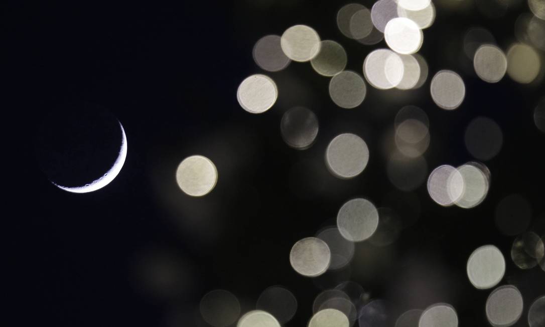 A Lua crescente vista entre a decoração de Natal em Milão, na Itália: novo calendário faria datas sempre caírem no mesmo dia da semana Foto: Luca Bruno / AP