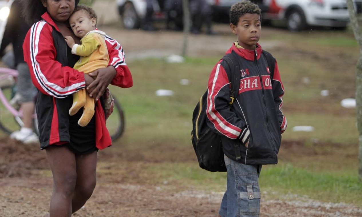 Mãe carrega filhos para fora da área de Pinheirinho durante desocupação Foto: O Globo / Marcos Alves