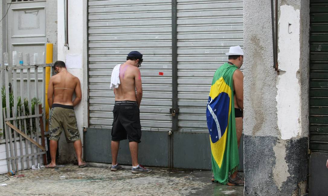 
Jovens urinam em porta de loja durante o desfile do bloco Toca Rauuul, na Praça Tiradentes, no domingo
Foto: Eduardo Naddar / O Globo