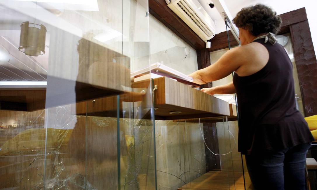 
A dona de uma joalheria em Cabo Frio, Ester Magalhães, arruma a loja: a vitrine foi quebrada por ladrões
Foto: Pablo Jacob / O Globo