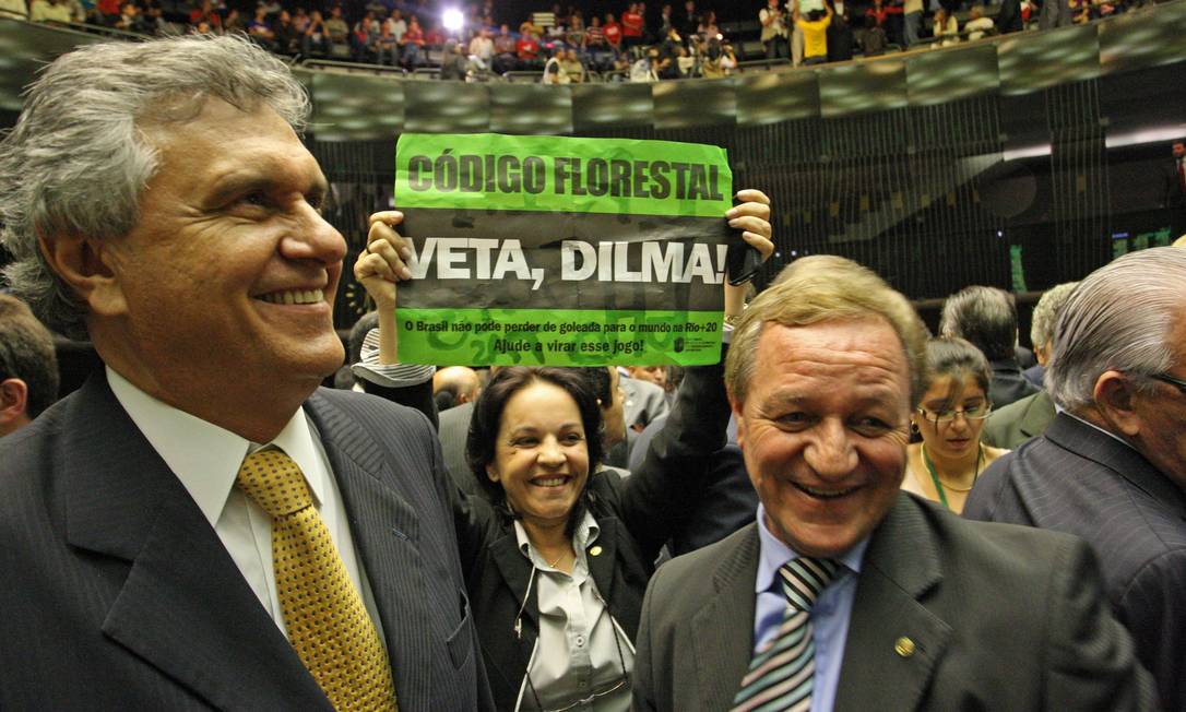 
Os deputados Ronaldo Caiado e Valdir Colatto, da bancada ruralista, comemoram a aprovação do relatório do deputado Paulo Piau, enquanto a deputada Rosane Ferreira (PV), protesta em meio a ambos
Foto: O Globo / André Coelho