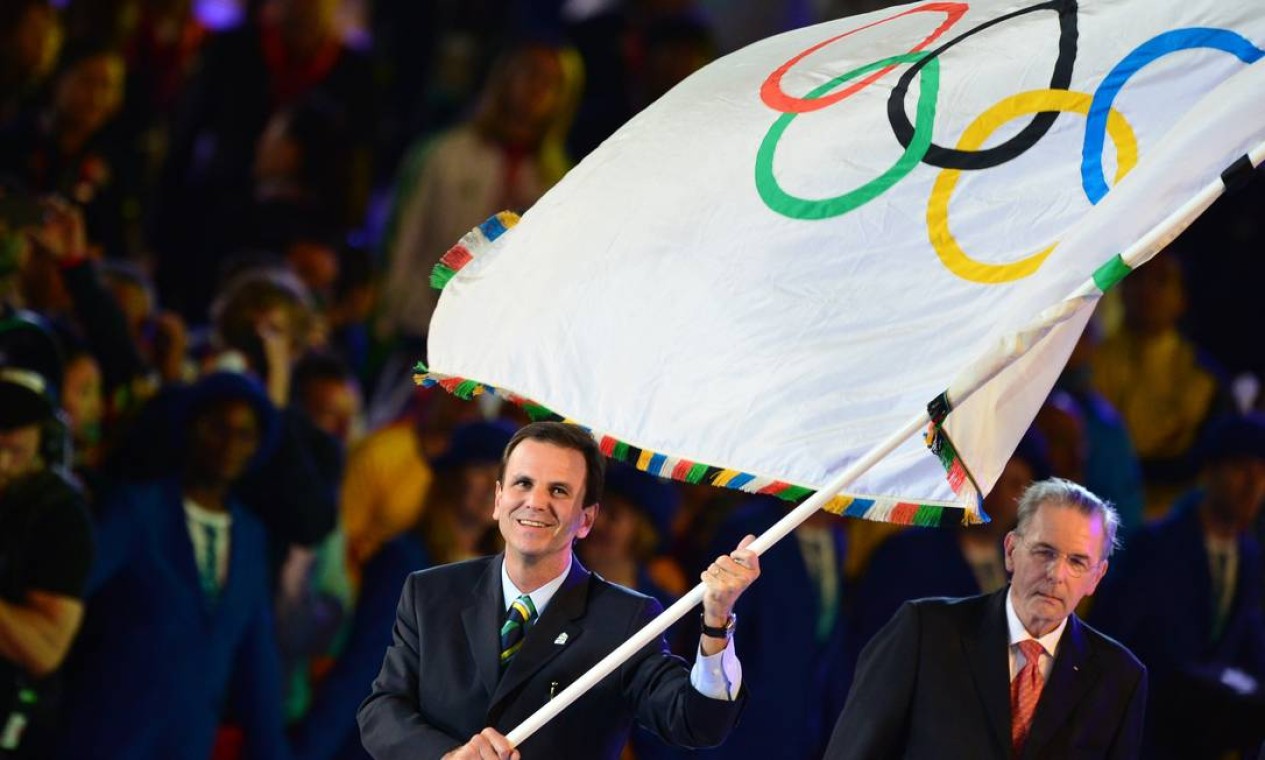 O prefeito do Rio, Eduardo Paes, balança a bandeira olímpica ao lado do presidente do Comitê Olímpico Internacional, Jacques Rogge, no encerramento das Olimpíadas de Londres Foto: AFP