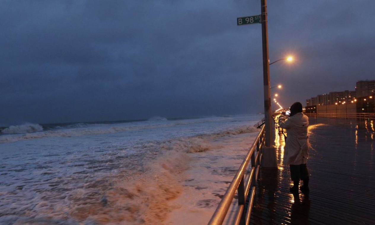 Uma mulher se arisca e tira uma foto em uma praia do Queens, área que será tomada pelas águas com a passagem de Sandy Foto: Reuters/Shannon Stapleton