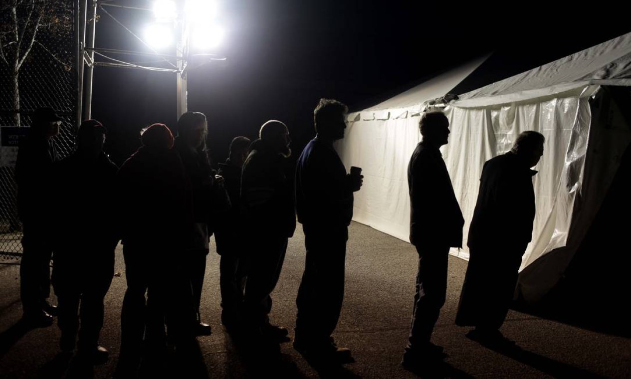 Sob luzes de um gerador, americanos esperam para votar em uma tenda em Midland Beach, no estado de Nova York. O governador de NY, Andrew Cuomo, autorizou que os eleitores votem em qualquer seção eleitoral do estado, por causa dos danos causados por Sandy Foto: AP