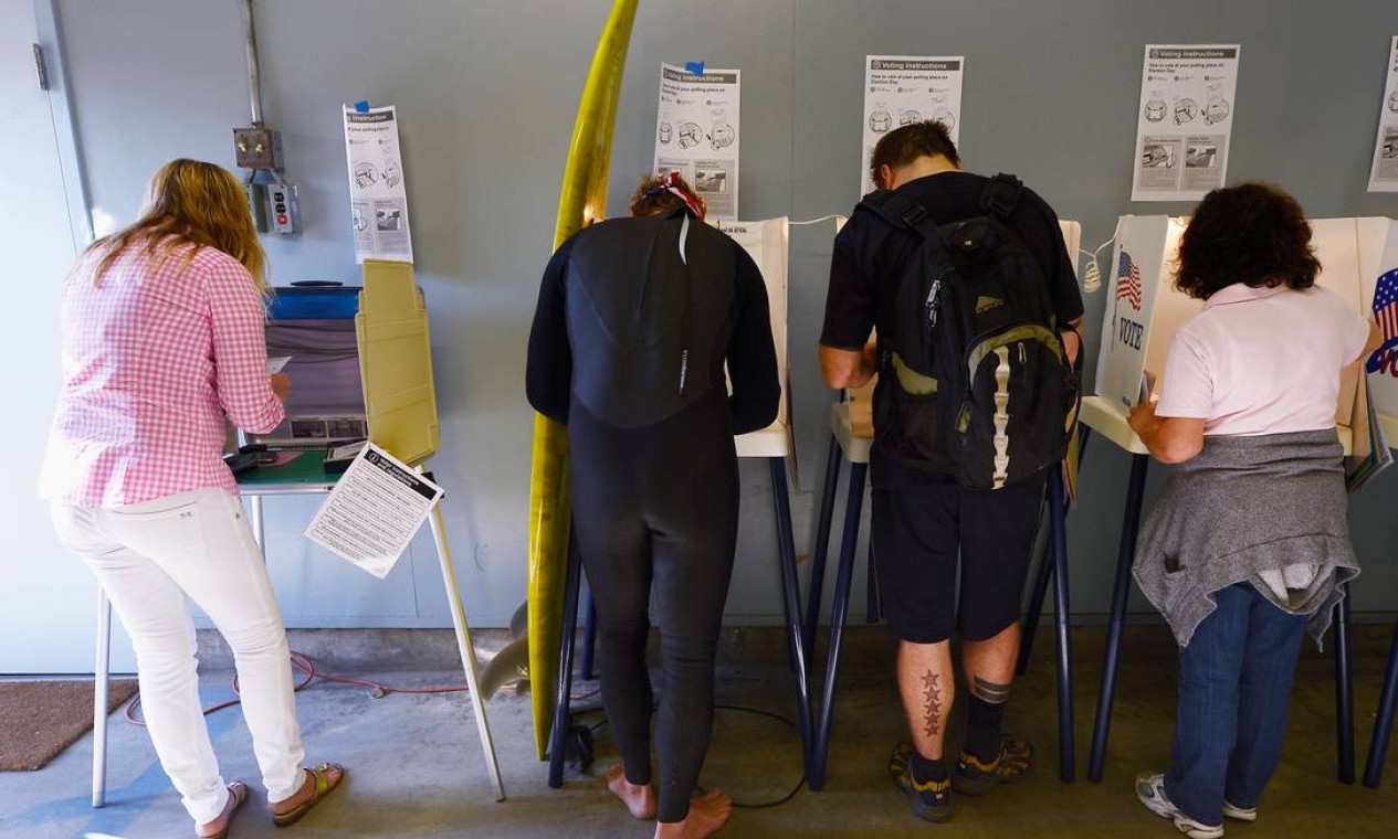 Surfista vota a caráter em seção eleitoral em Los Angeles, Califórnia Foto: AFP