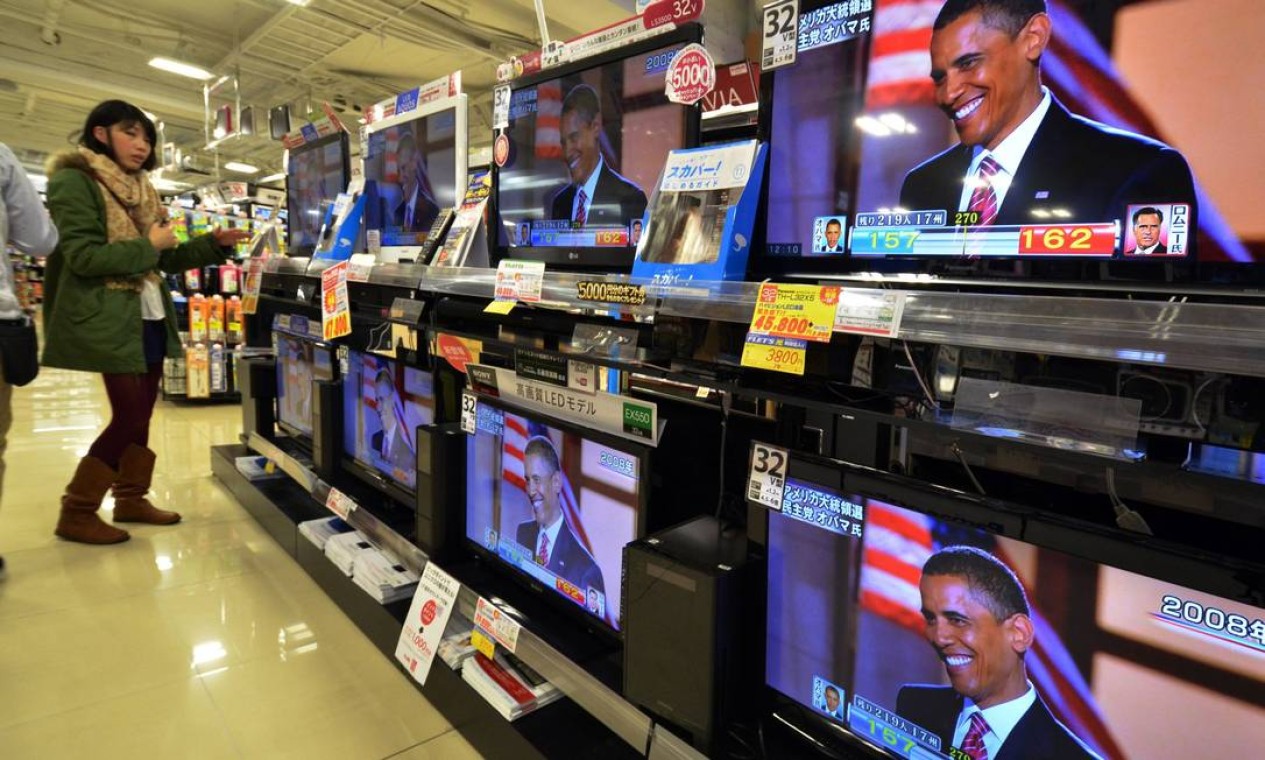 Em loja de eltrodomésticos em Tóquio, Japão, mulher assiste imagens de Obama Foto: AFP