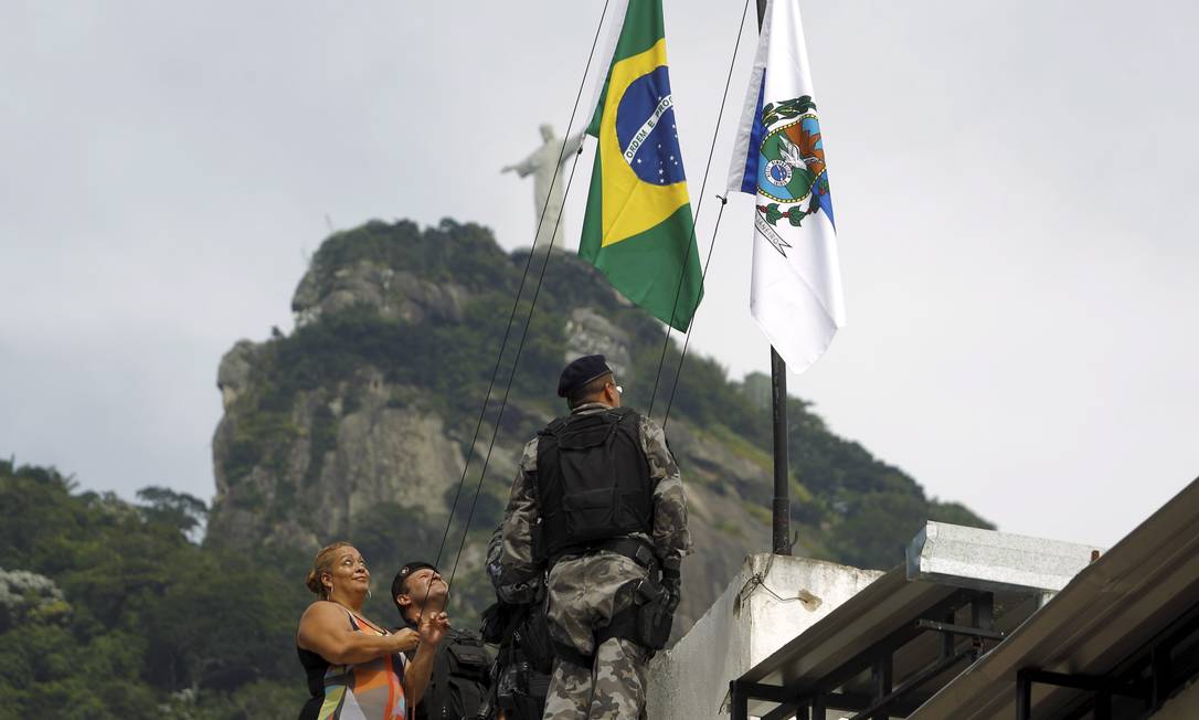 Moradores ajudam PMs a hastear bandeiras no alto da Ladeira dos Guararapes Foto: Gabriel de Paiva / Agência O Globo