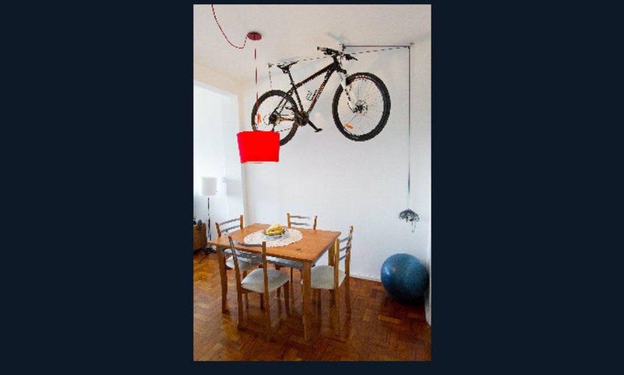 Na sala de jantar, que fica na entrada do apartamento, a bicicleta pendurada no teto dá toque divertido ao ambiente Foto: Guito Moreto
