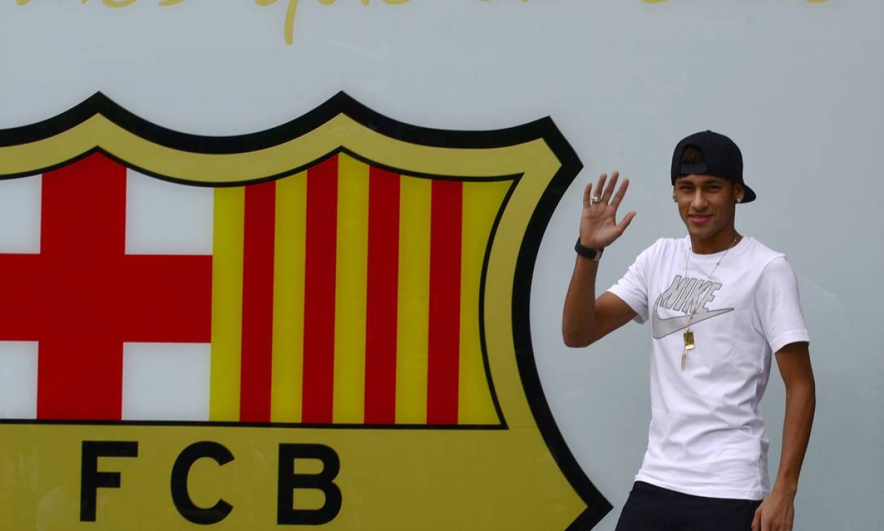 Neymar, ao lado do escudo do Barça e o lema: “més que un club” (mais que um clube, em catalão) Foto: LLUIS GENE / AFP