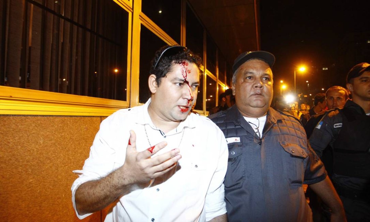 Homem ferido é levado por policial militar Foto: Pablo Jacob / Agência O Globo