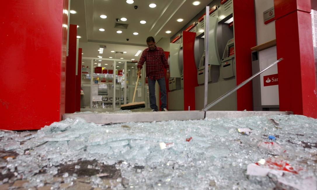 
Homem limpa uma das agências bancarias que tiveram o vidro quebrado por manifestantes na Avenida Presidente Vargas
Foto: Marcos Tristão / Agência O Globo